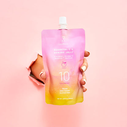 Osvežilni veganski konjak jelly z okusom breskve, obogaten s kolagenom in vitaminom C v roki na roza podlagi